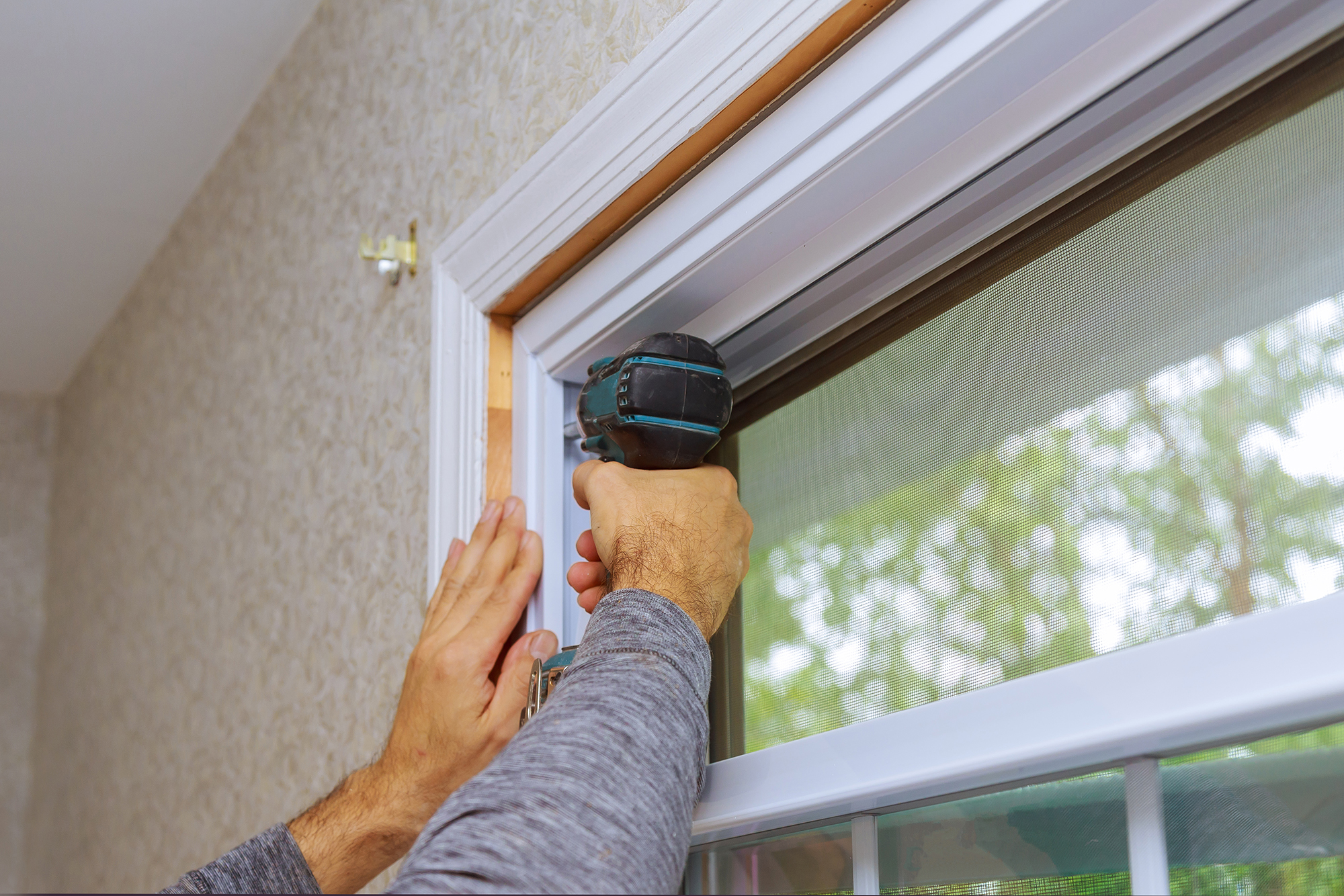 Professional master for installation of new window in house uses an electric drill