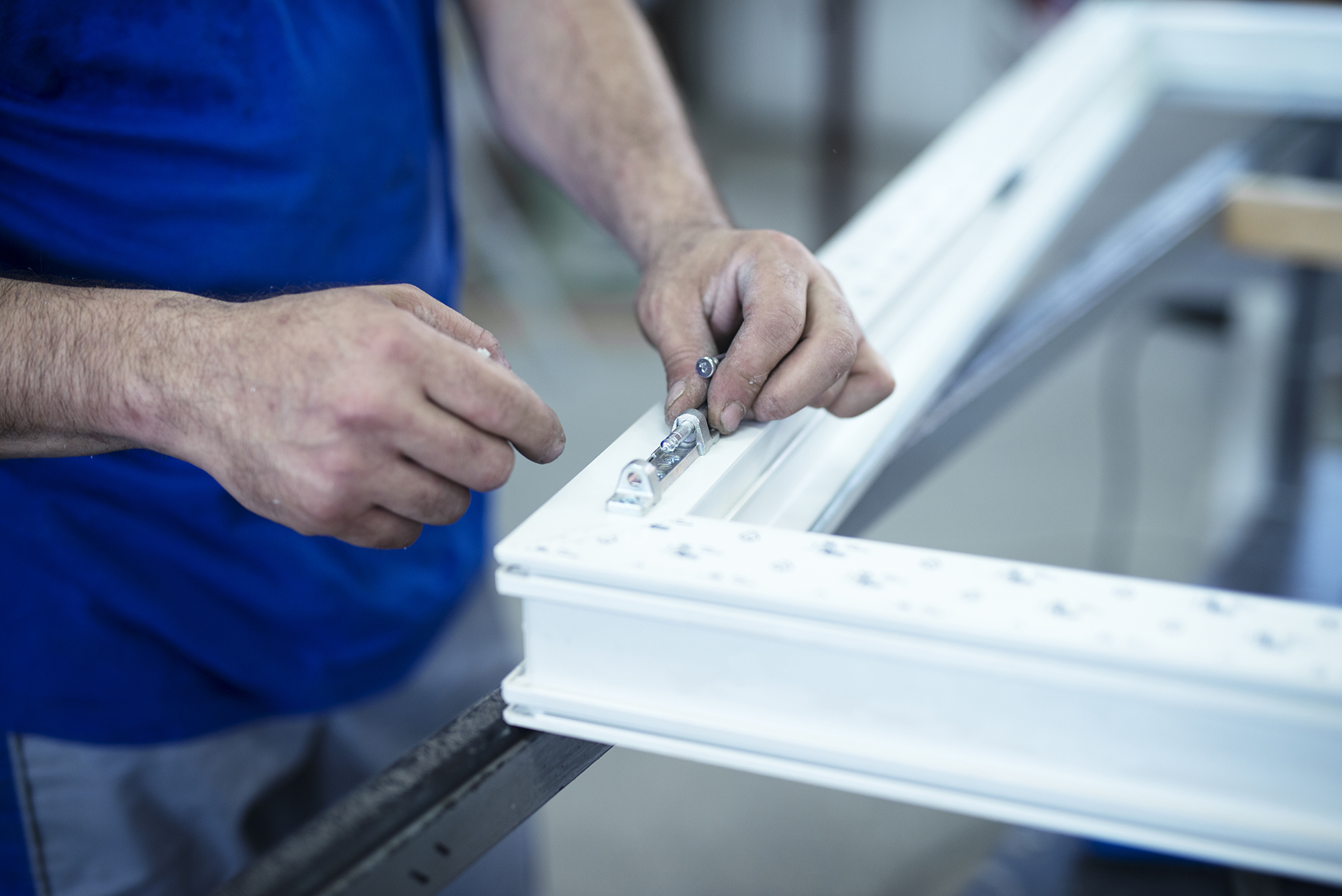 Manual worker assembling hinge on PVC doors and windows.
